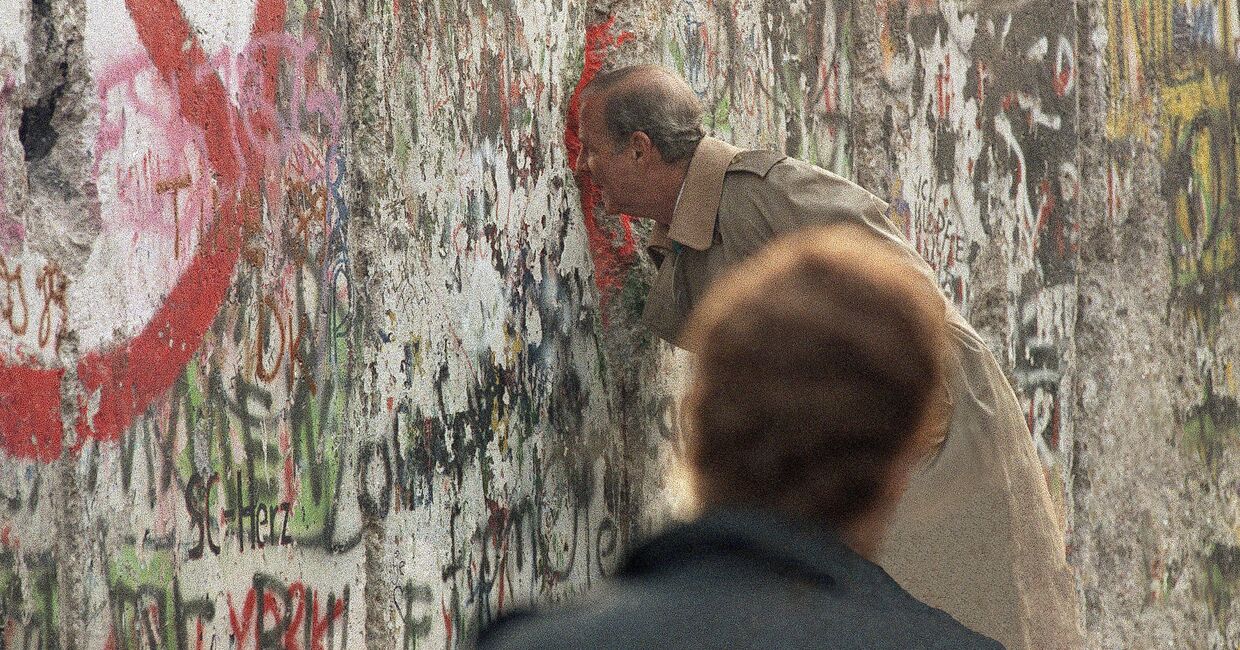 Госсекретарь США Джеймс Бейкер III смотрит через разлом в Берлинской стене на Потсдамской площади