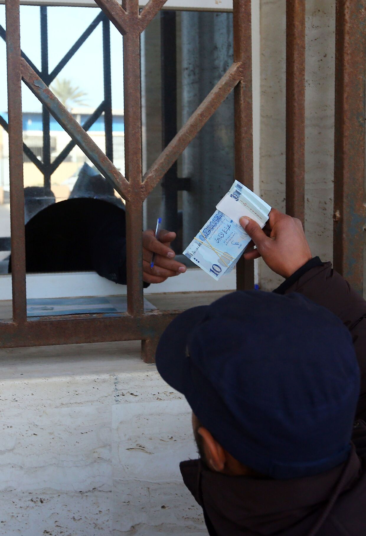 Мужчина получает деньги из банка в Триполи, Ливия