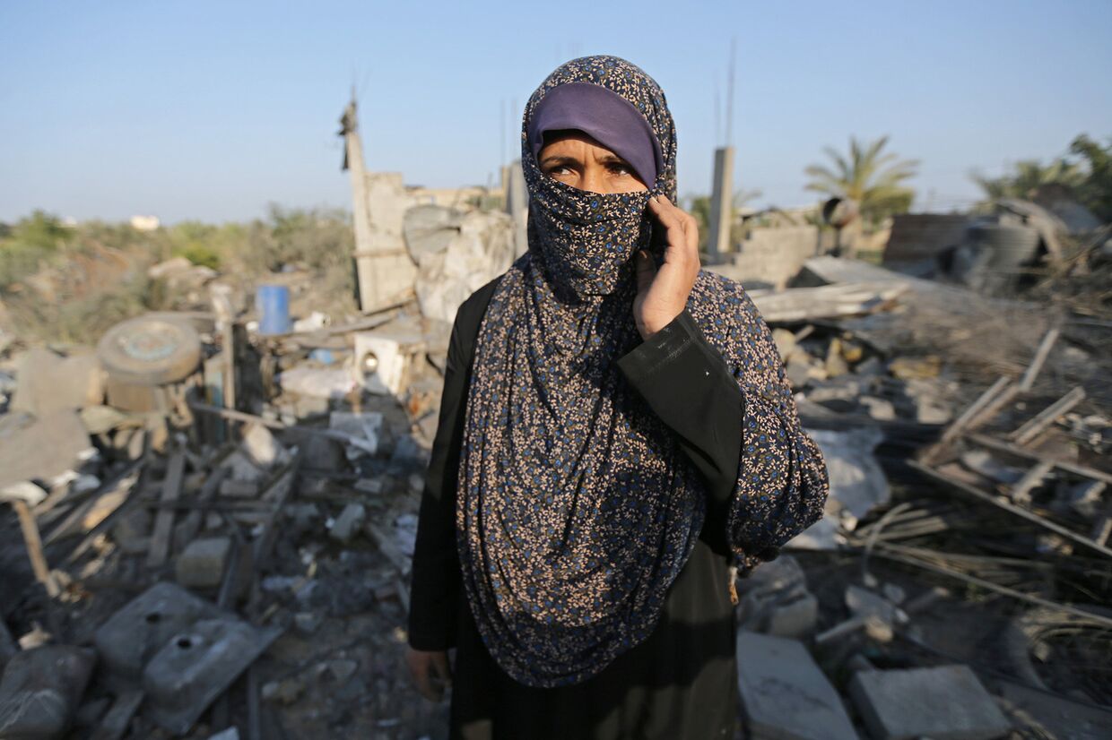 Женщина у разрушенного в результате израильского авиаудара дома в Секторе Газа