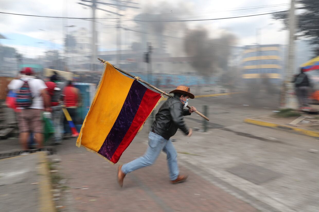 Демонстрант держит флаг Эквадора во время протеста