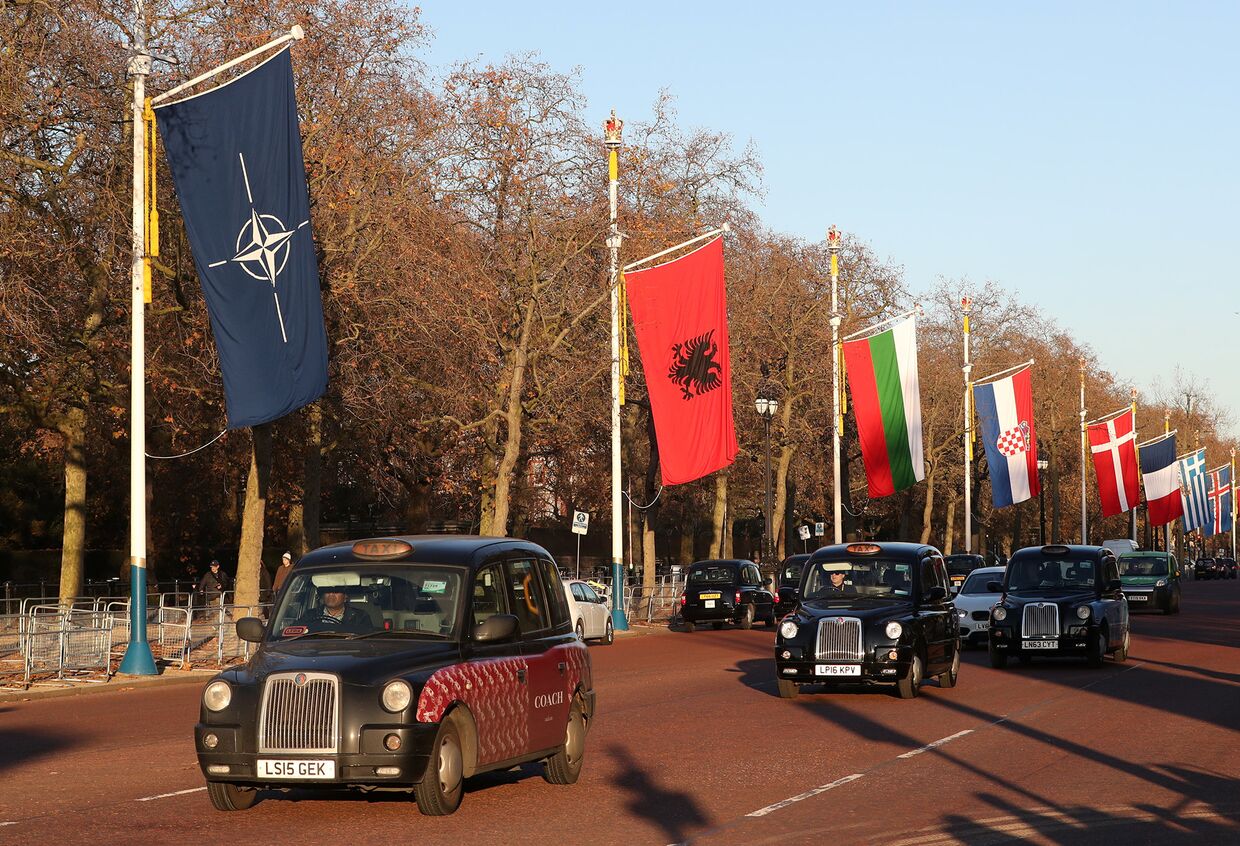 Лондонские такси проезжают мимо флагов в преддверии саммита НАТО в Лондоне, Великобритания