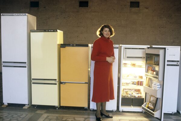 Представитель производственного объединения по выпуску холодильников Атлант рядом с образцами продукции