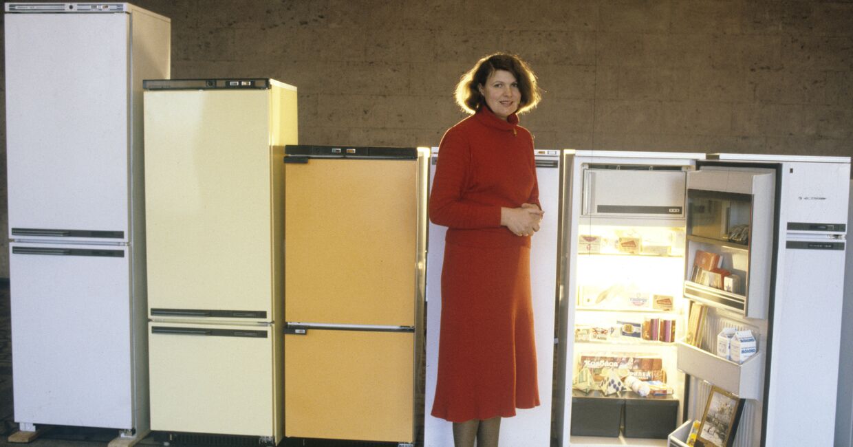 Представитель производственного объединения по выпуску холодильников Атлант рядом с образцами продукции