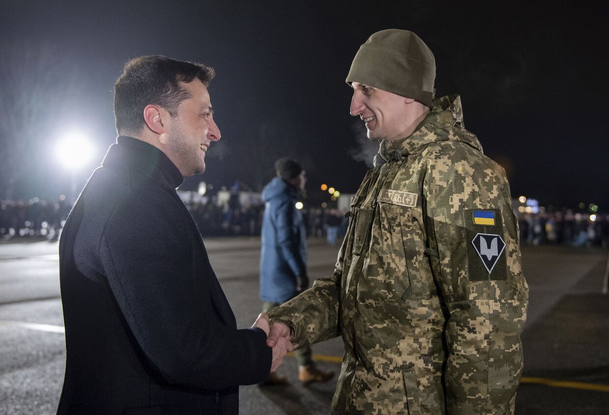Президент Украины Владимир Зеленский приветствует украинского военного после обмена пленными в аэропорту Борисполь