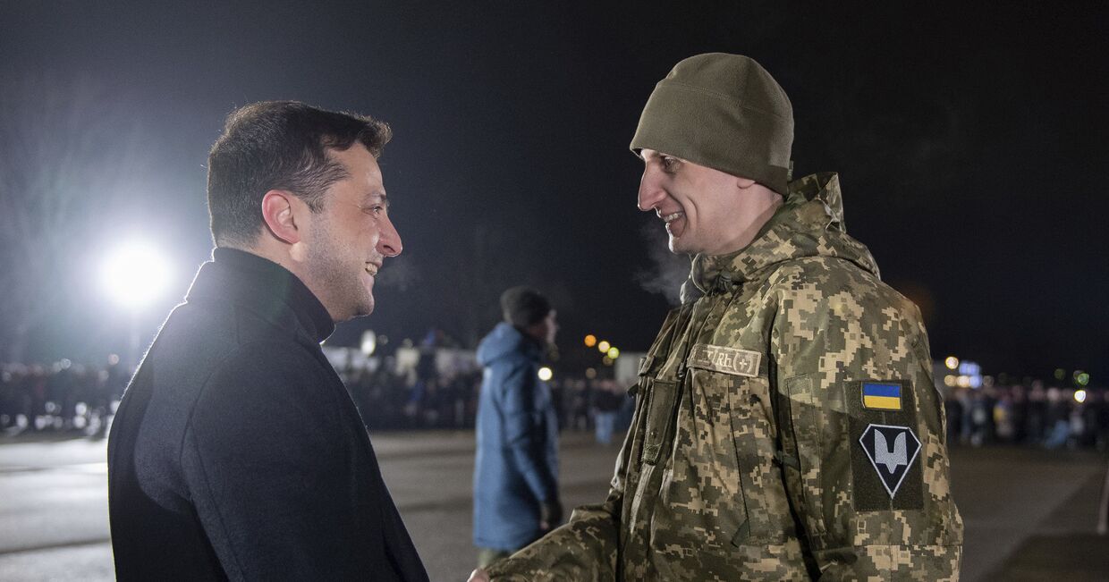 Президент Украины Владимир Зеленский приветствует украинского военного после обмена пленными в аэропорту Борисполь
