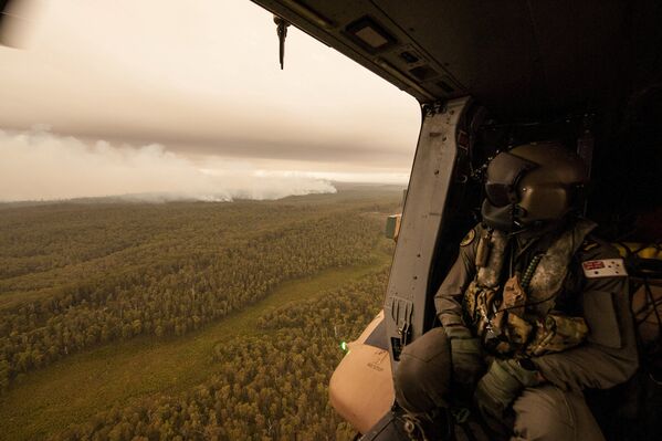 Член экипажа вертолета ВМФ Австралии наблюдает за пожарами у реки Канн в Гипсленде, Австралия