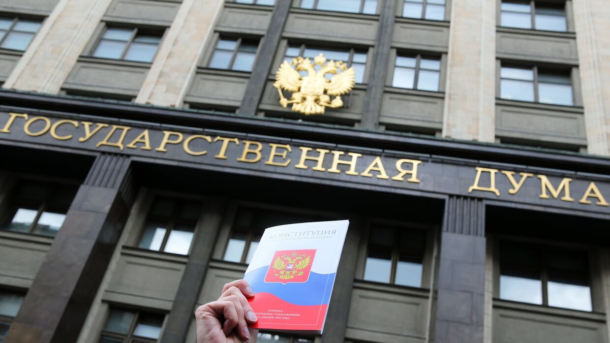 Конституция Российской Федерации на фоне здания Государственной Думы РФ в Москве
