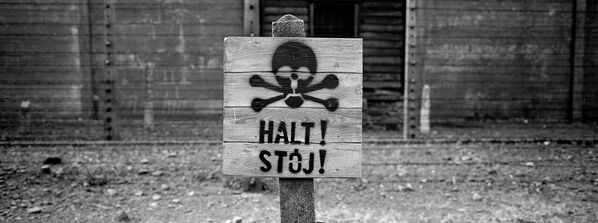 Деревянный знак «Стоп» у забора с колючей проволокой в Освенциме