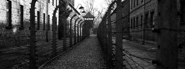 Путь к наблюдательной башне вдоль забора под напряжением из колючей проволоки в Освенциме, Польша