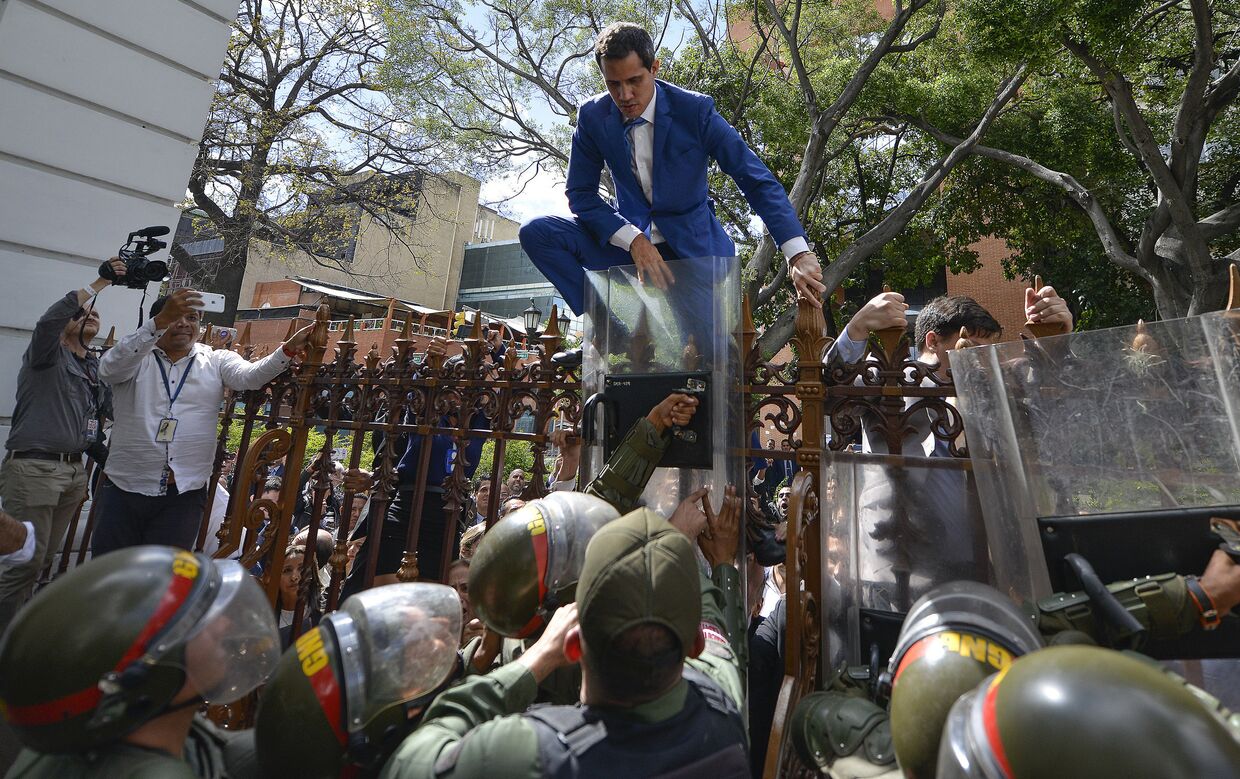 Лидер оппозиции Венесуэлы Хуан Гуайдо перелезает через забор, чтобы попасть в здание Национальной ассамблеи в Каракасе