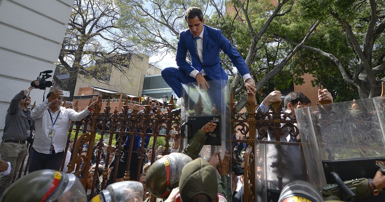 Лидер оппозиции Венесуэлы Хуан Гуайдо перелезает через забор, чтобы попасть в здание Национальной ассамблеи в Каракасе