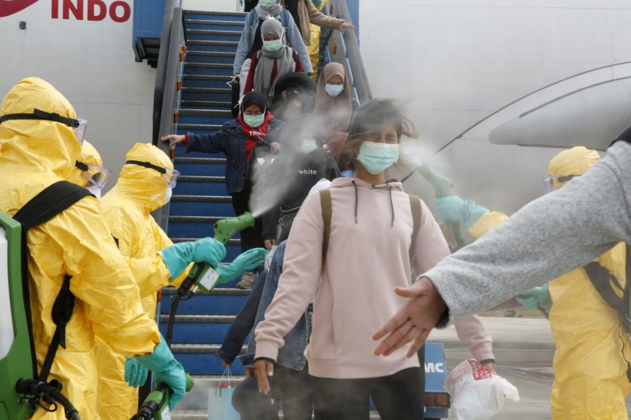 Медицинские работники распыляют антисептик для пассажиров рейса из Уханя в аэропорту Ханг Надим в Батаме, Индонезия