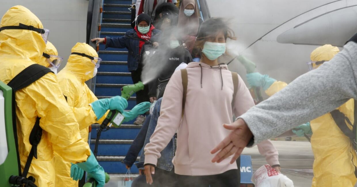 Медицинские работники распыляют антисептик для пассажиров рейса из Уханя в аэропорту Ханг Надим в Батаме, Индонезия