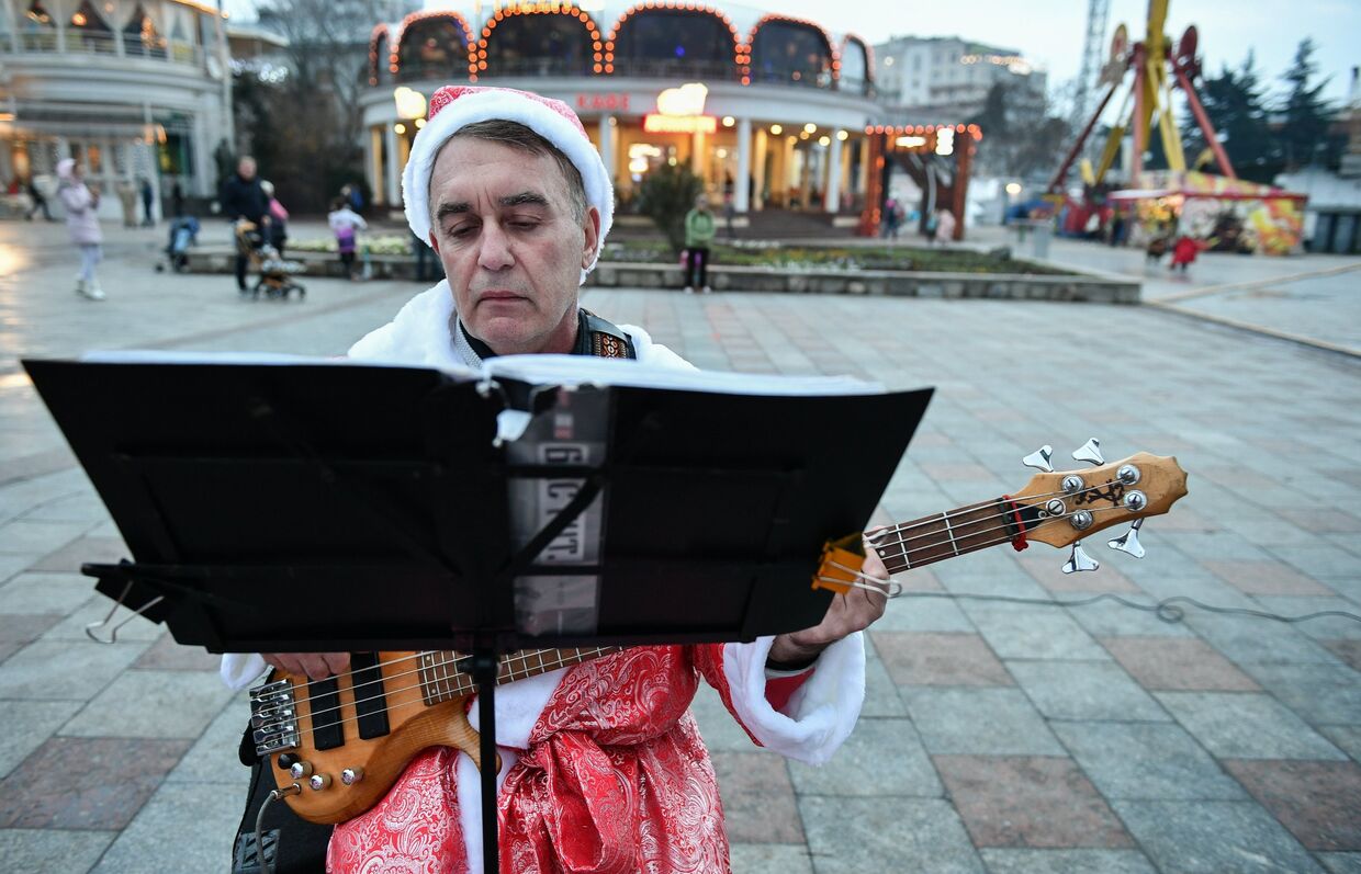 Музыкант в костюме Деда Мороза выступает на набережной в Ялте, Крым