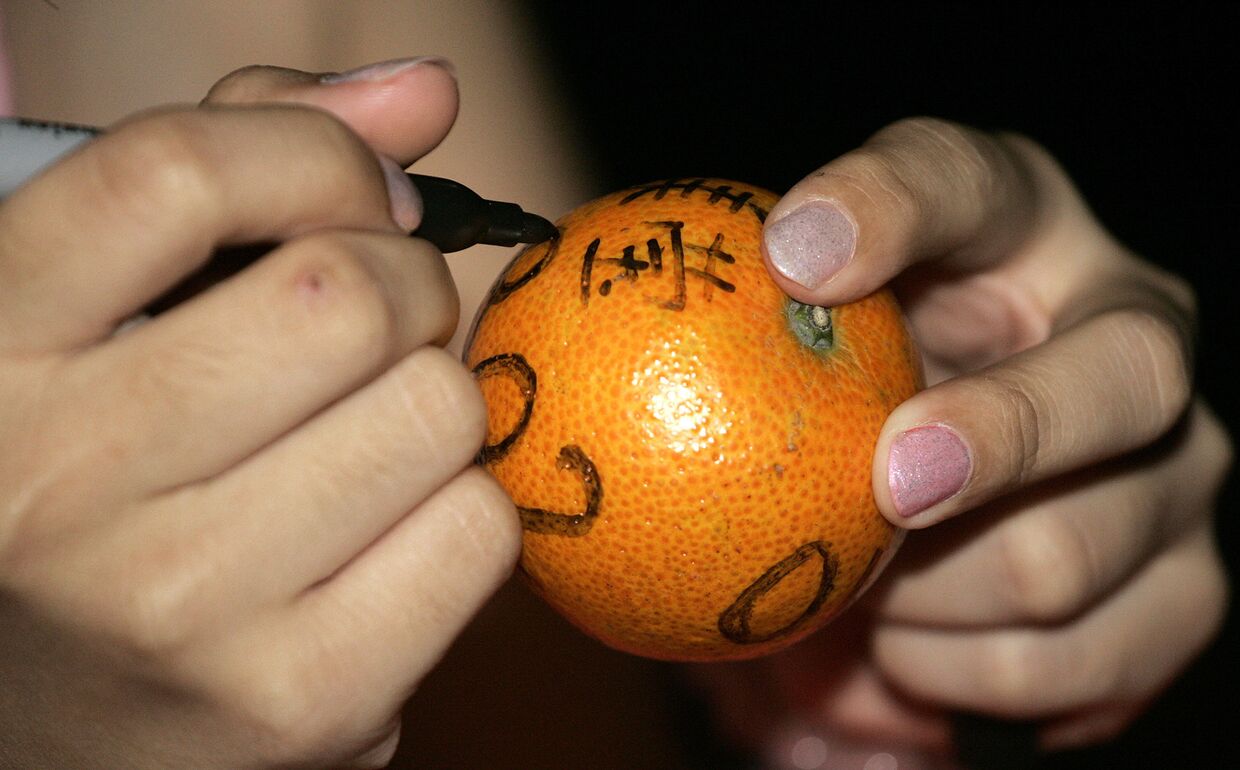 Девушка подписывает мандарин во время фестиваля Chap Goh Mei в Куала-Лумпуре, Малайзия