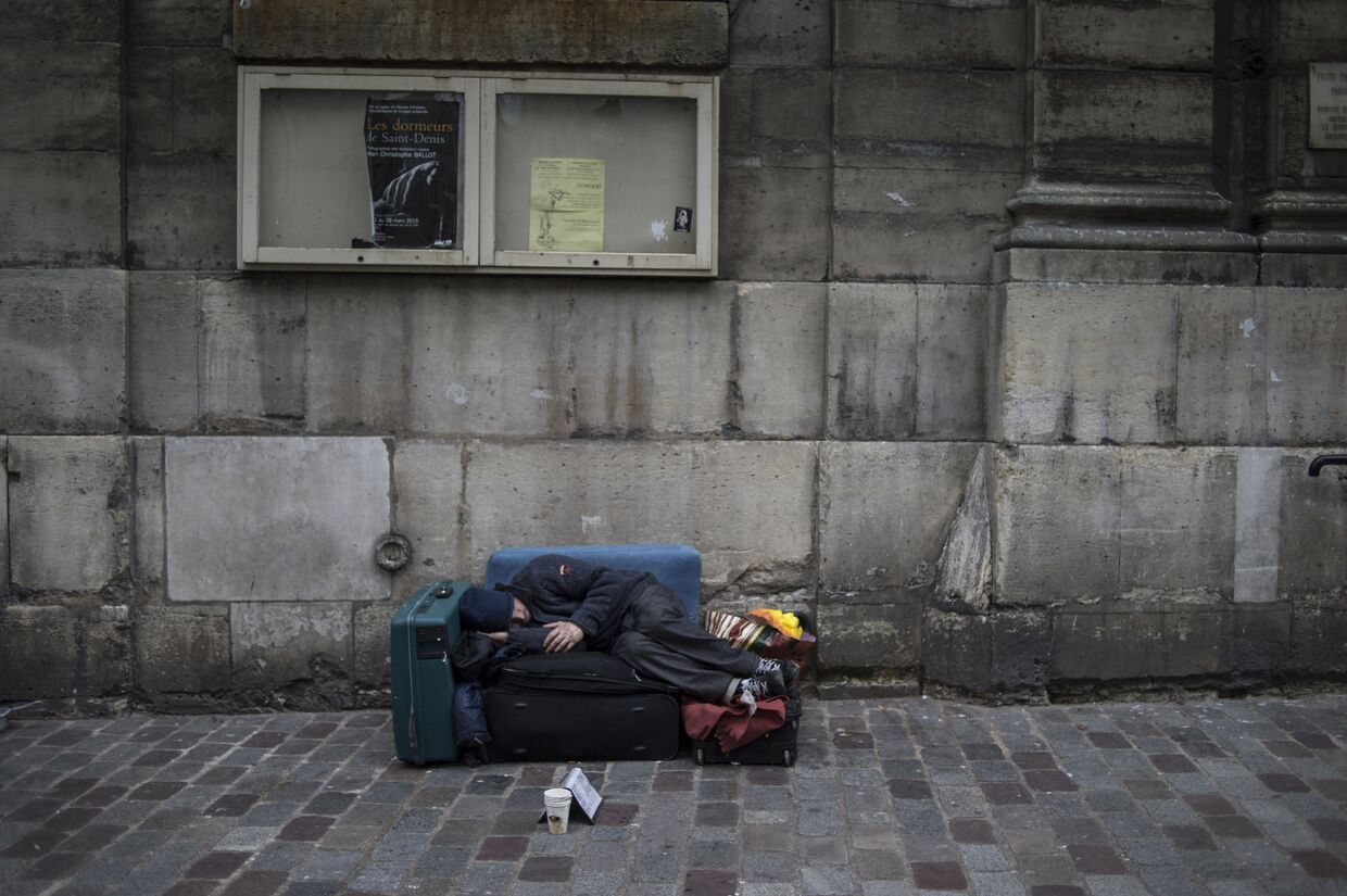 Бездомный спит на одной из улиц Парижа