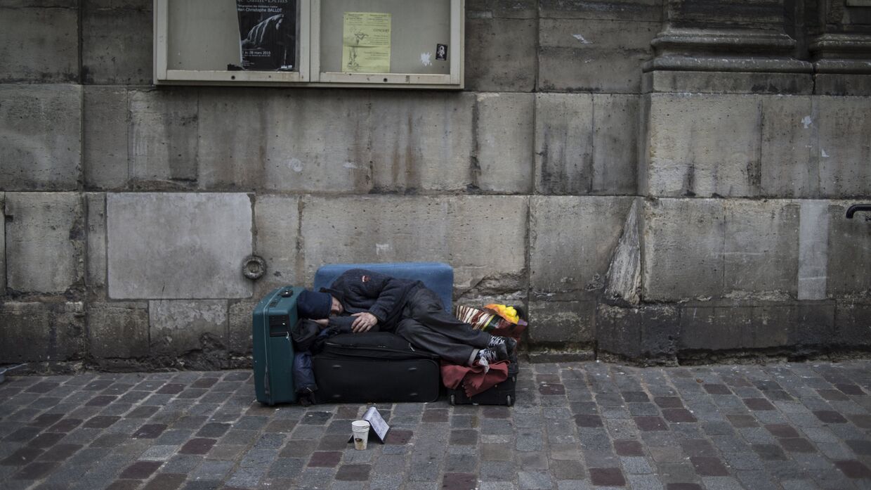 Бездомный спит на одной из улиц Парижа