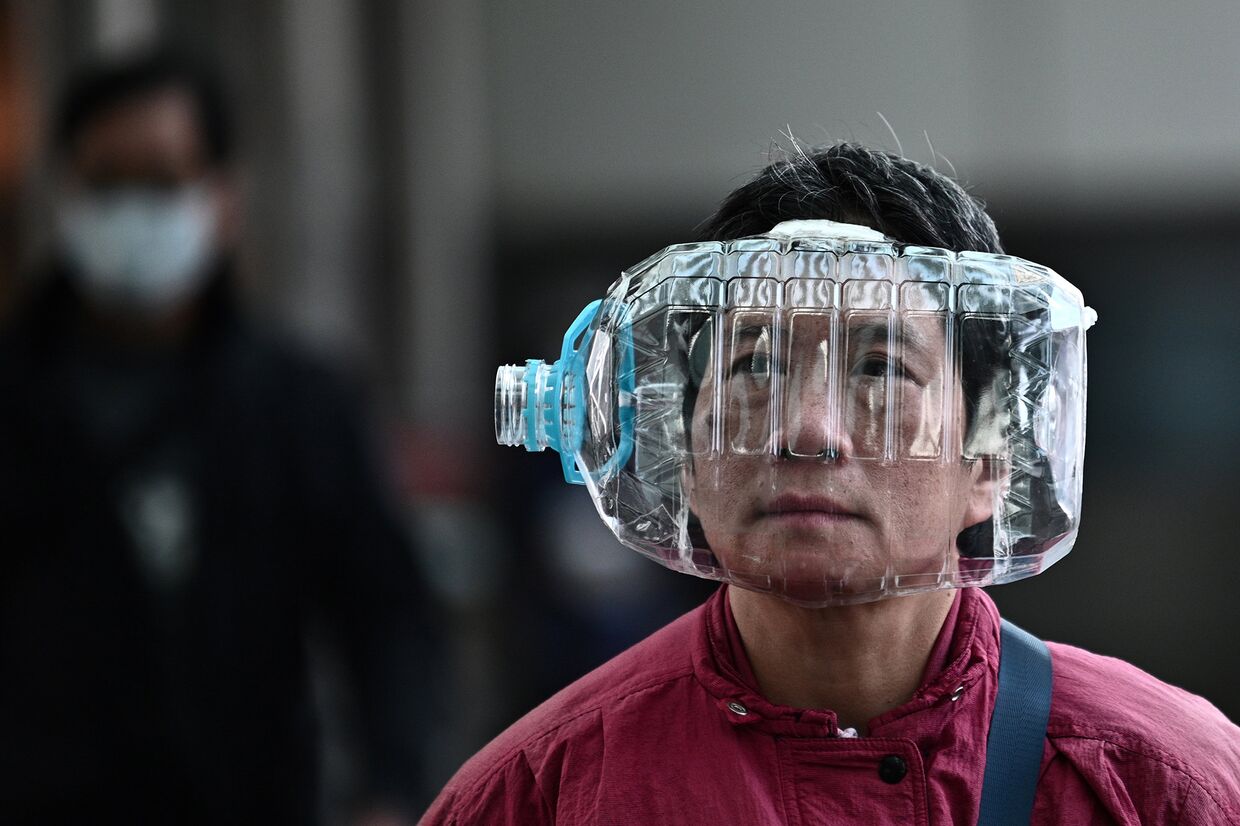 Мужчина с пластиковой бутылкой в качестве меры защиты от коронавируса в Гонконге