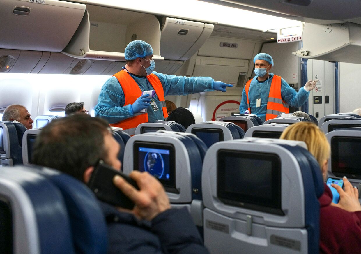 Медицинские работники во время измерения температуры тела пассажиров в Международном аэропорту Борисполь под Киевом, Украина