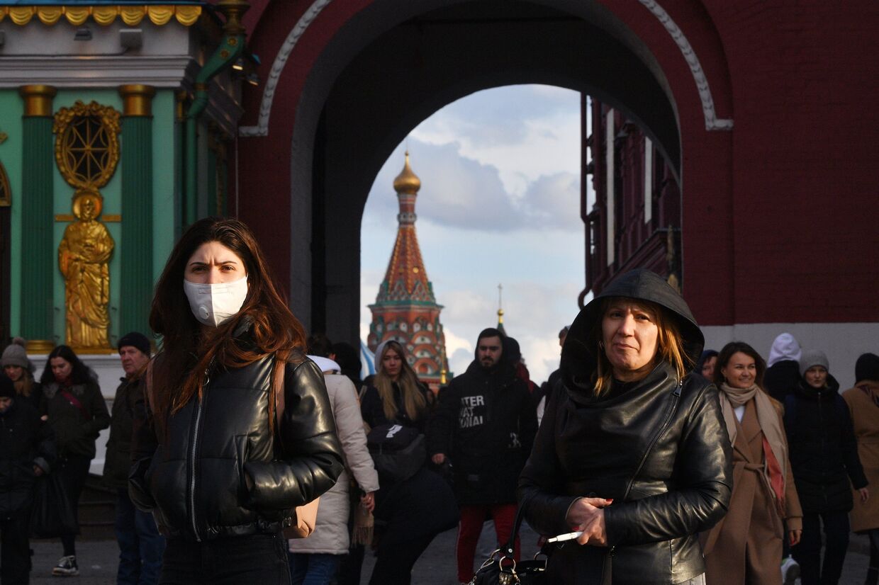 Люди проходят через Воскресенские ворота, ведущие на Красную площадь, в Москве