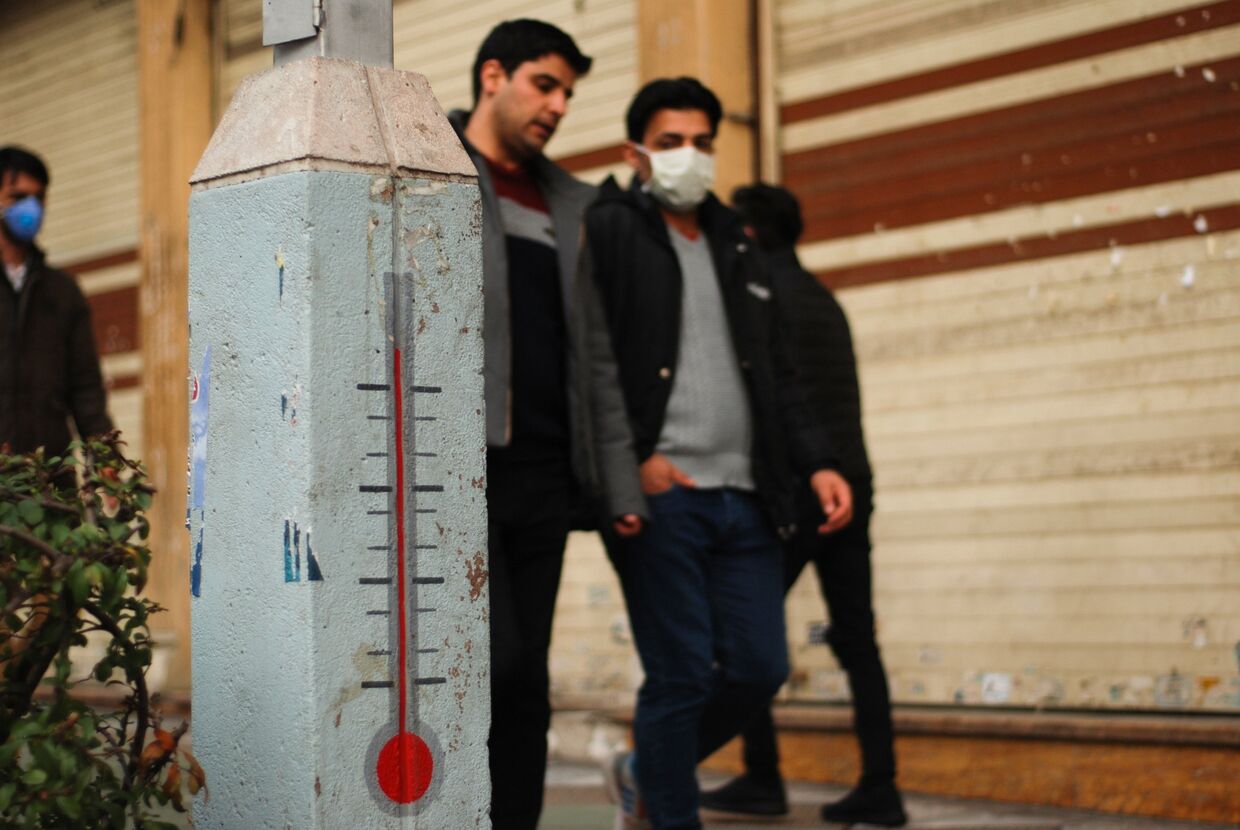 Молодые люди в медицинских масках на одной из улиц Ирана во время эпидемии коронавируса