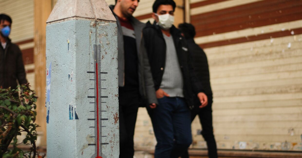 Молодые люди в медицинских масках на одной из улиц Ирана во время эпидемии коронавируса