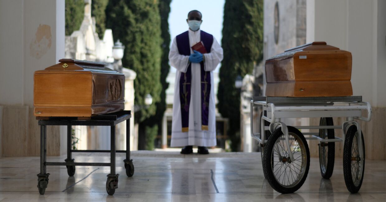 Священник и два гроба с жертвами коронавируса, Италия