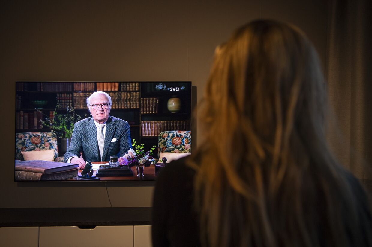 Женщина смотрит по телевизору обращение к нации короля Швеции Карла XVI Густава по поводу эпидемии коронавируса
