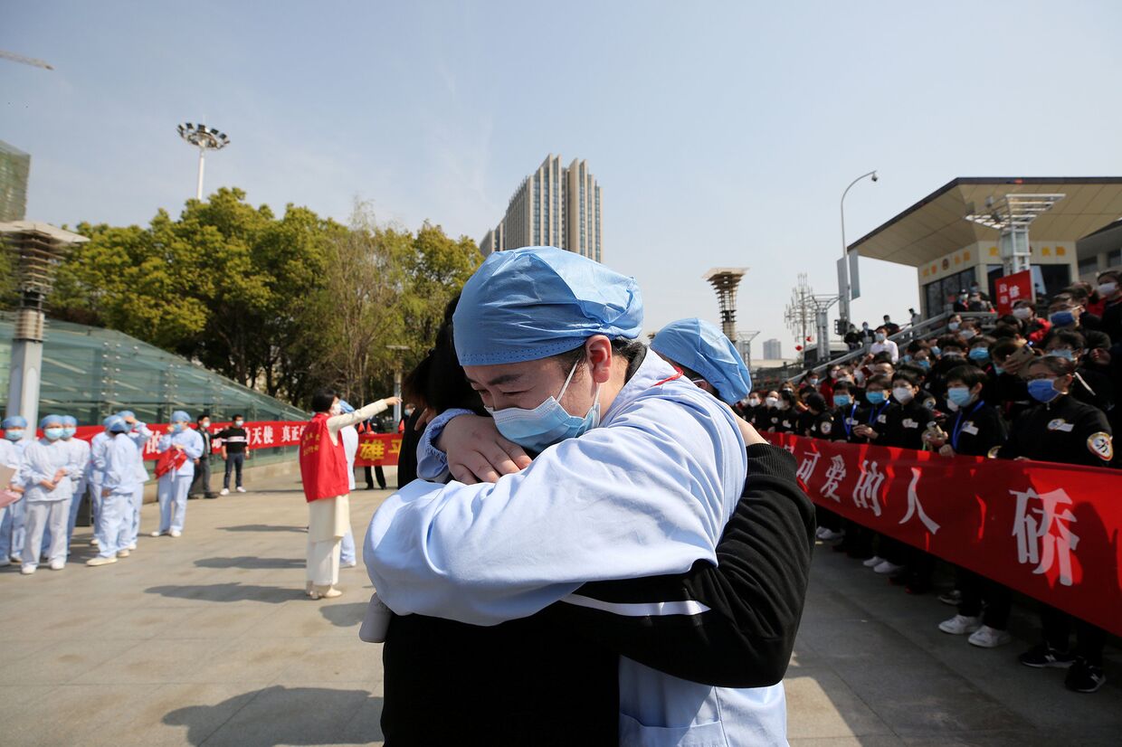 Медики обнимаются во время церемонии прощания с медицинской бригадой из Цзянсу на железнодорожном вокзале города Ухань, Китай