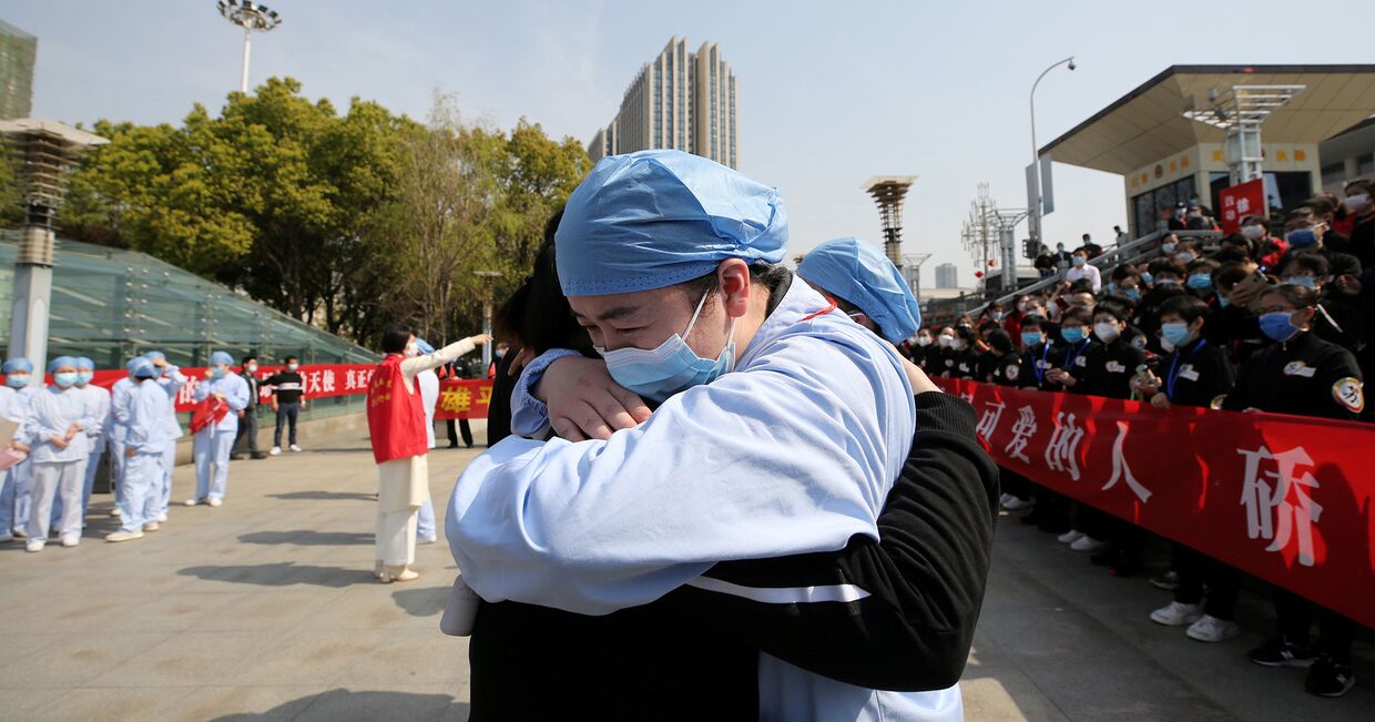 Медики обнимаются во время церемонии прощания с медицинской бригадой из Цзянсу на железнодорожном вокзале города Ухань, Китай