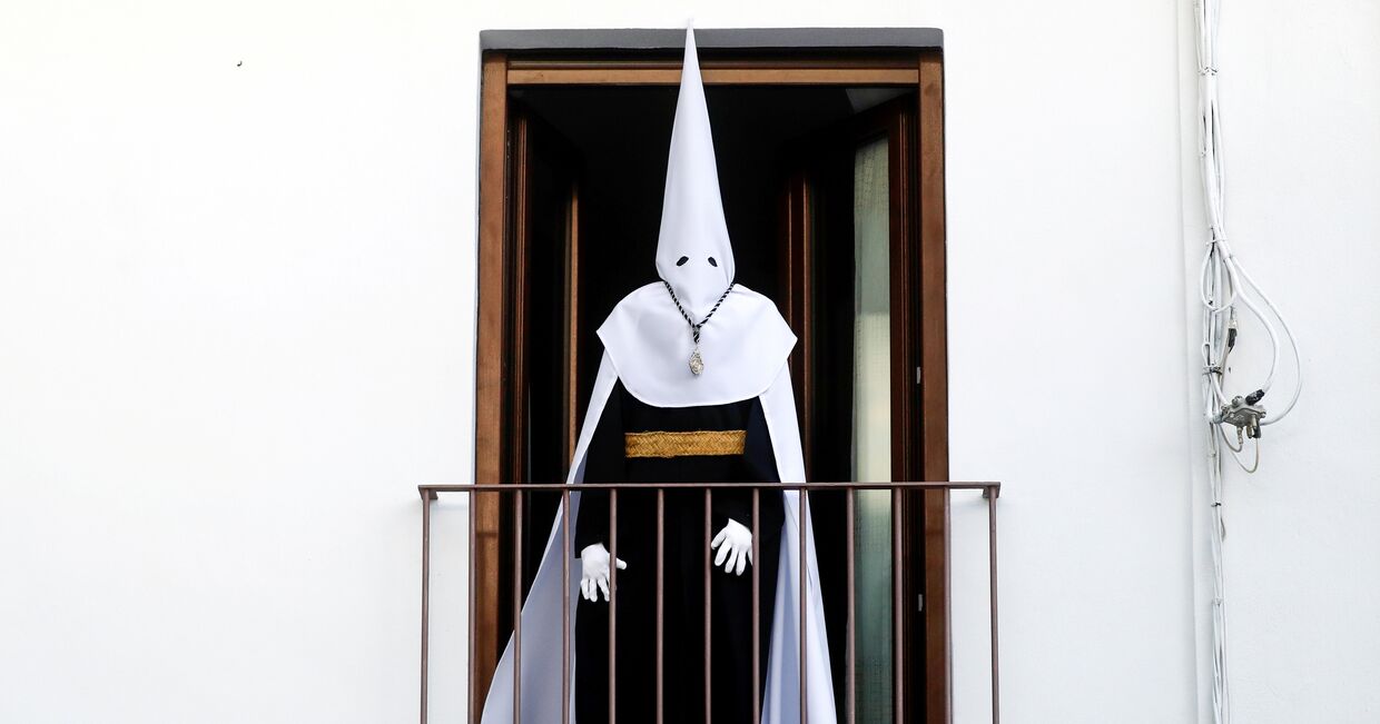 Испанец в костюме для ежегодного пасхального шествия на балконе во время карантина в Ронде, Испания