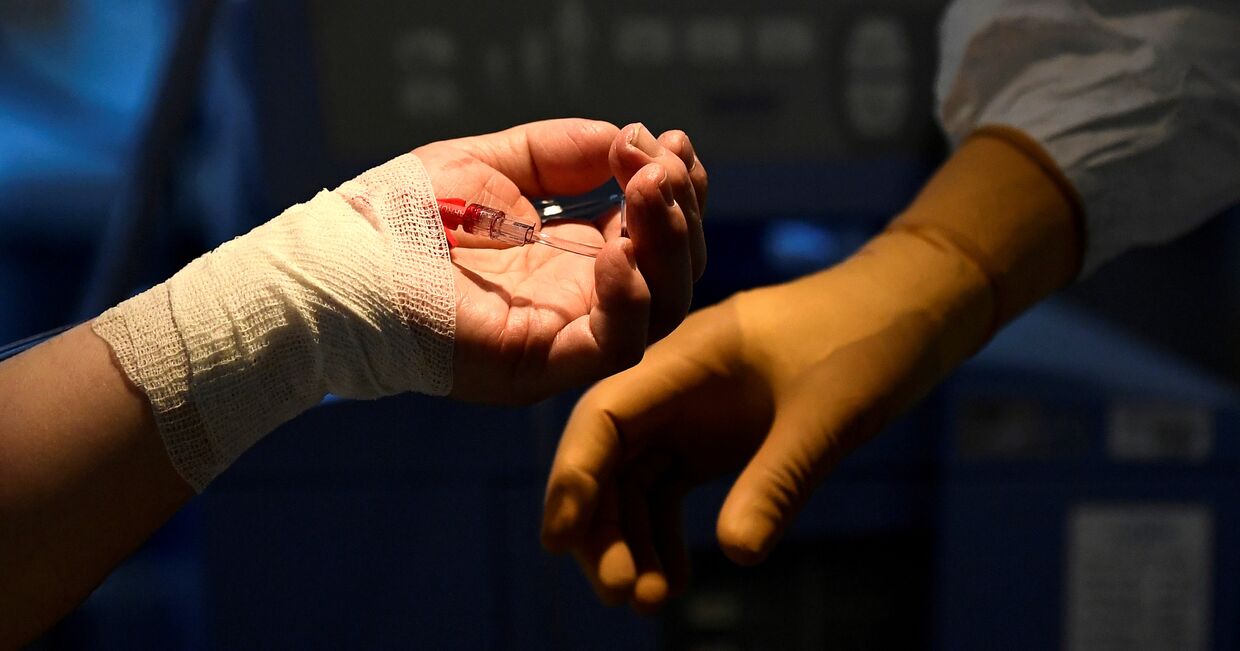 9 апреля 2020. Руки пациента с коронавирусом и медика в больнице Варезе, Италия