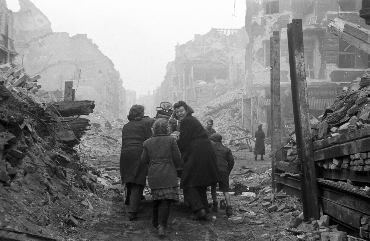 Жители Берлина возвращаются домой по заваленной обломками улице. Бои закончились.
