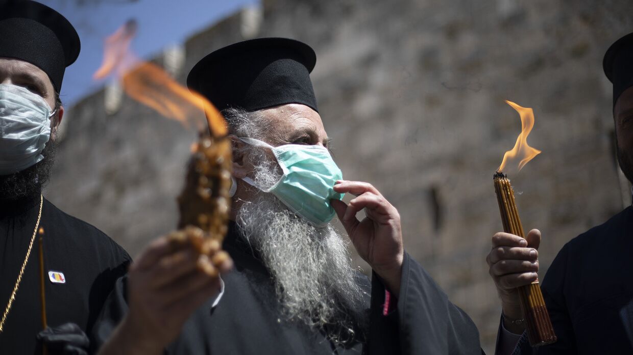Православные священнослужители несут Благодатный огонь в Иерусалиме