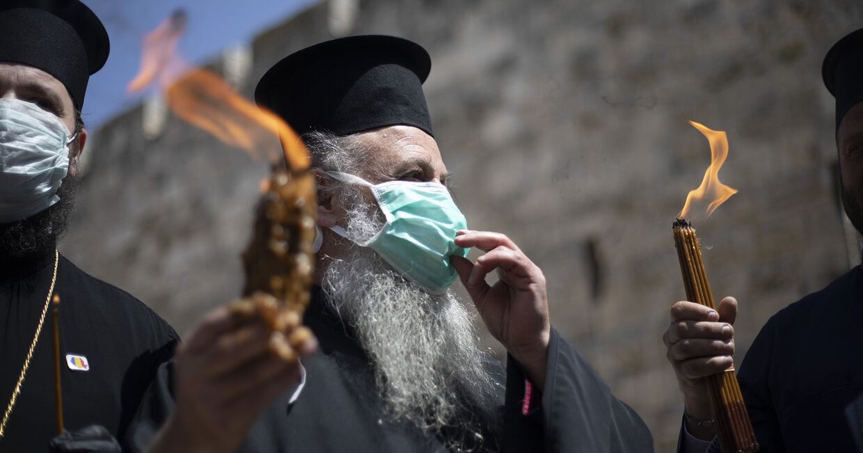 Православные священнослужители несут Благодатный огонь в Иерусалиме