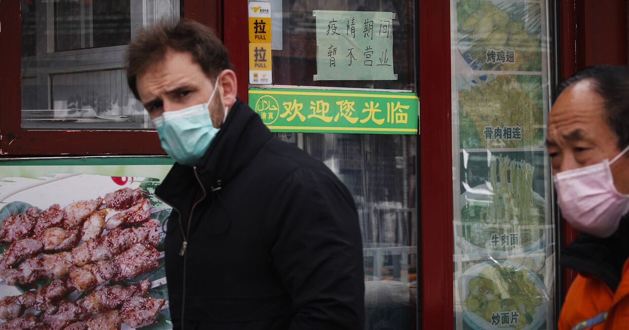 Иностранец на фоне закрытых магазинов в Пекине