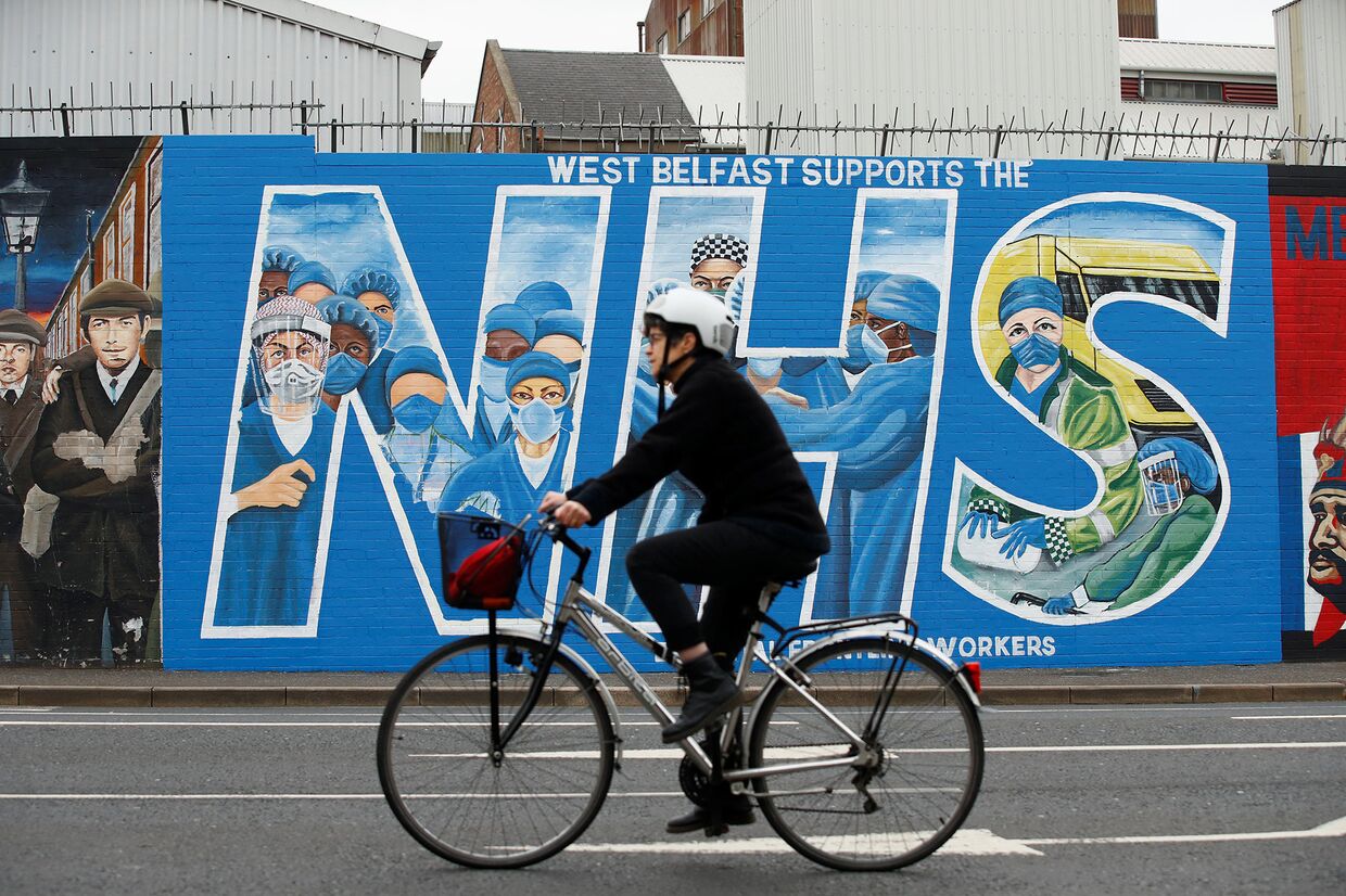 Велосипедист  на фоне граффити в поддержку врачей в Белфасте