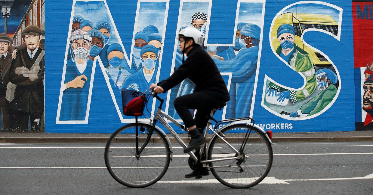 Велосипедист  на фоне граффити в поддержку врачей в Белфасте