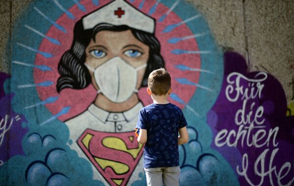 Мальчик перед граффити, изображающим медсестру в роли Суперженщины в Хамме, Германия