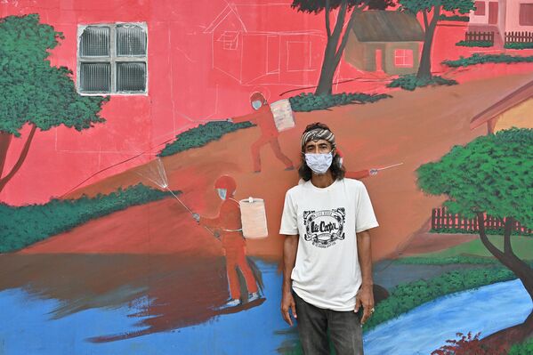 Уличный художник Даше Самант рядом со своим граффити в Депоке, Индонезия