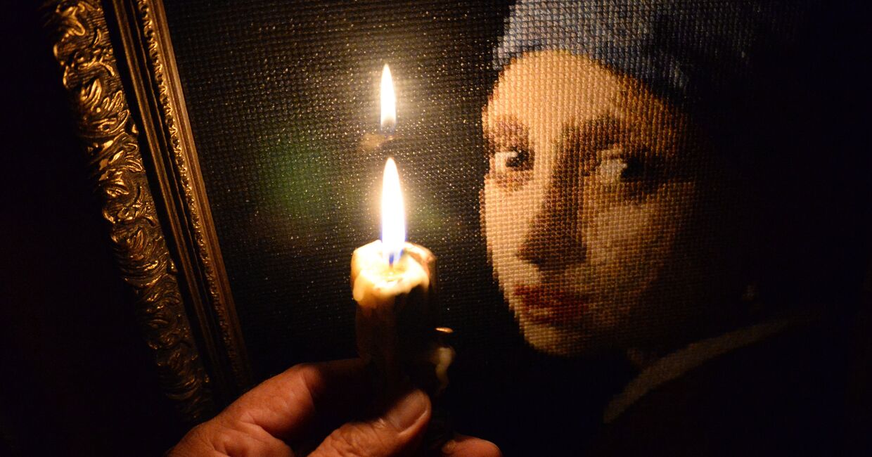Горящая свеча на фоне вышитой крестиком картины в одной из квартир во Владивостоке.