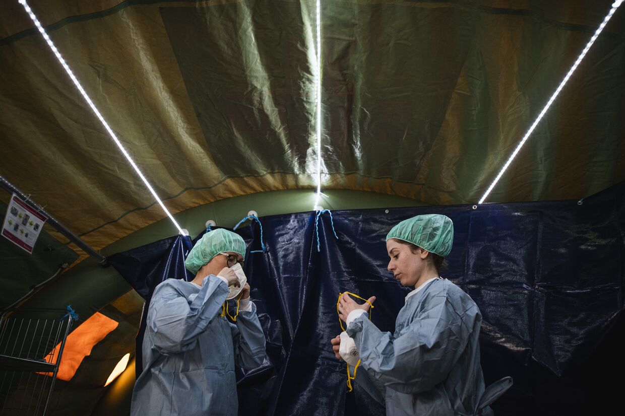 22 апреля 2020. Врач и медсестра надевают защитные костюмы в мобильном госпитале для больных коронавирусом в Стокгольме, Швеция