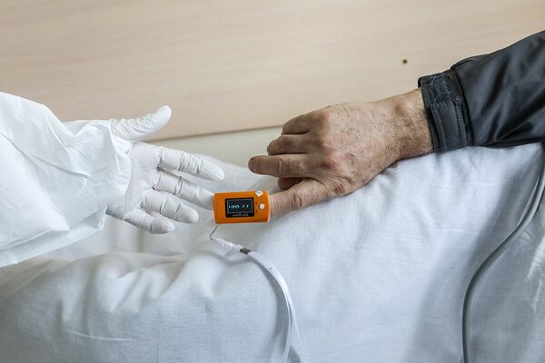 Медицинский работник проверяет пульсоксиметр у пациента с коронавирусом в ЦКБ «РЖД-Медицина» в Москве