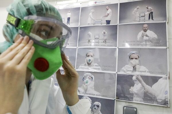 Медицинский работник надевает защитный костюм рядом с инструкцией в ЦКБ «РЖД-Медицина» в Москве