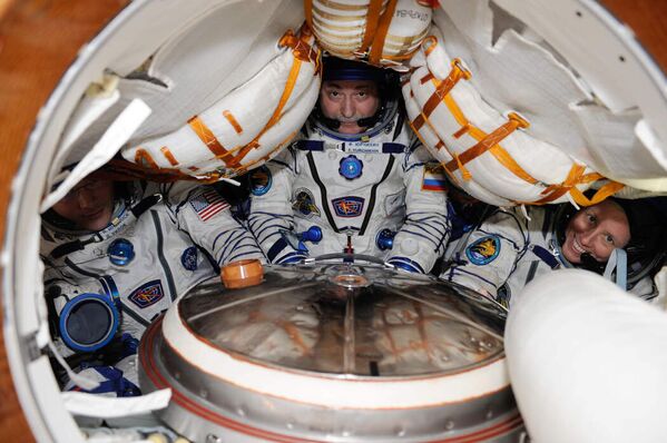 Два астронавта и космонавт внутри спускаемого модуля «Союз» в 2010 году