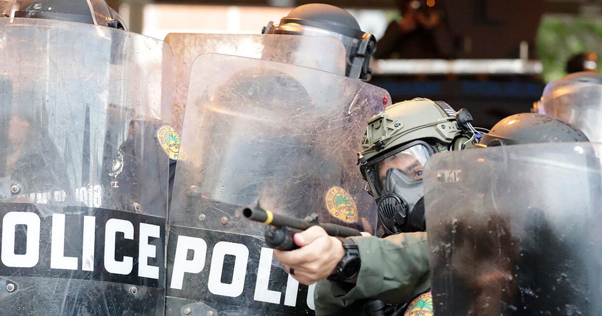 Полицейский стреляет резиновыми пулями в протестующих в Майами
