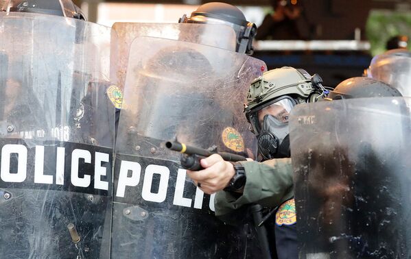 Полицейский стреляет резиновыми пулями в протестующих в Майами