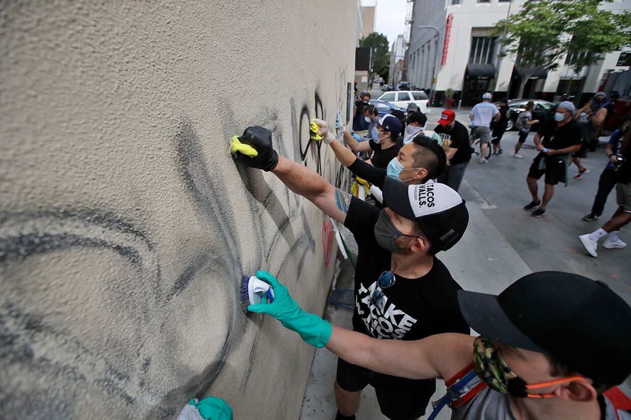 Волонтеры смывают граффити со стены магазина в Санта-Монике