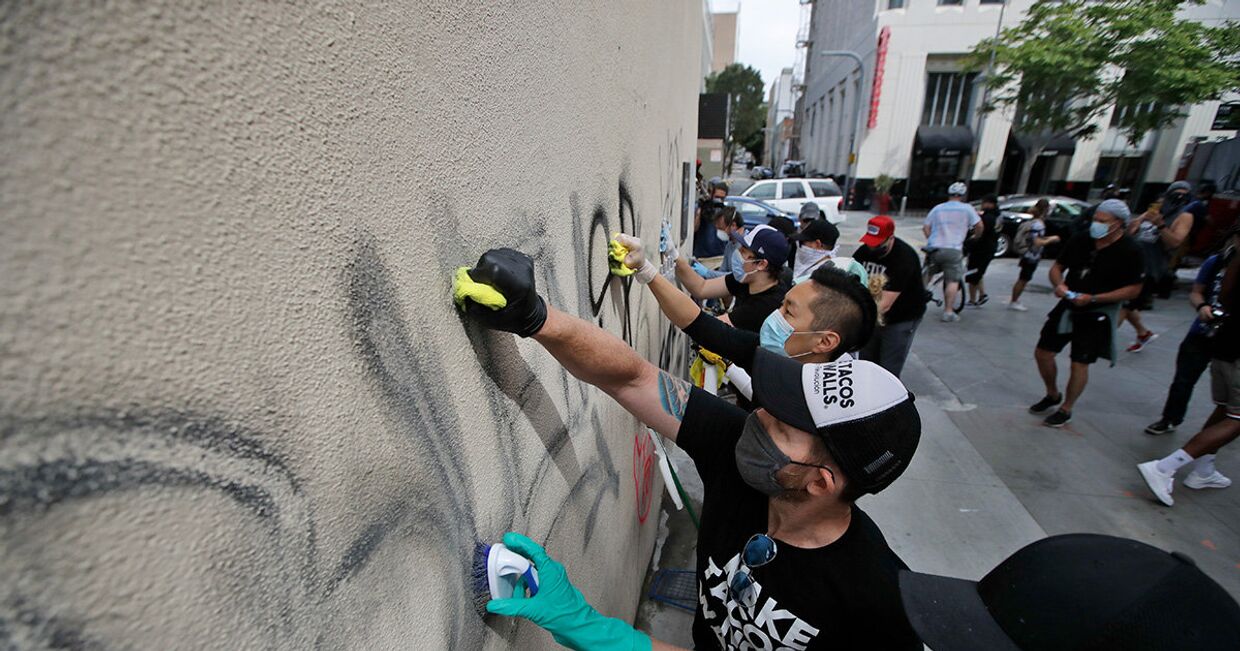 Волонтеры смывают граффити со стены магазина в Санта-Монике