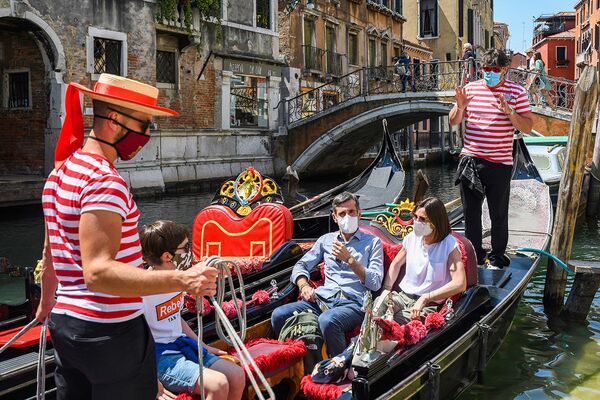 Туристы катаются на гондоле по каналам Венеции